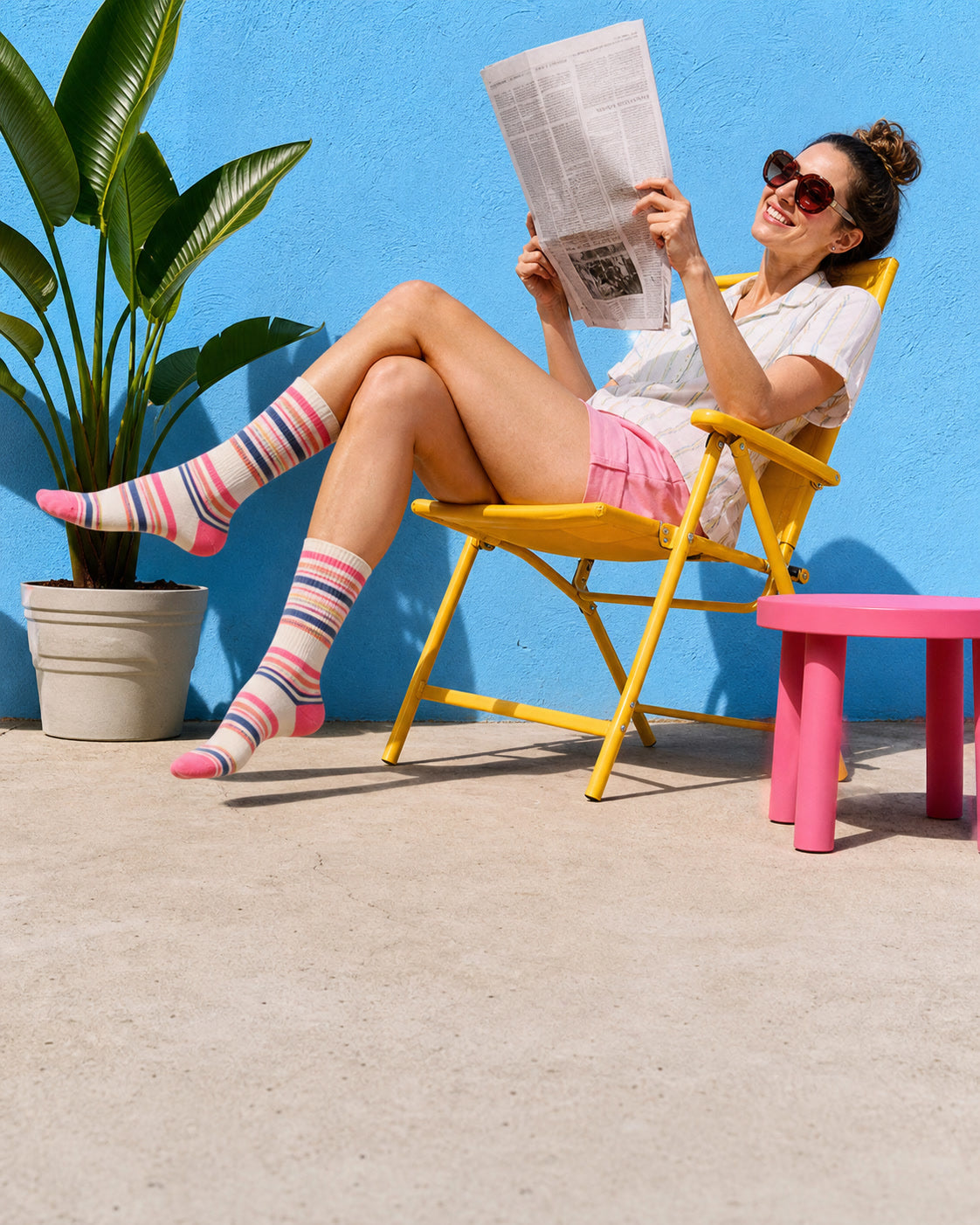 An adult relaxing in a yellow patio chair with an upside-down newspaper.